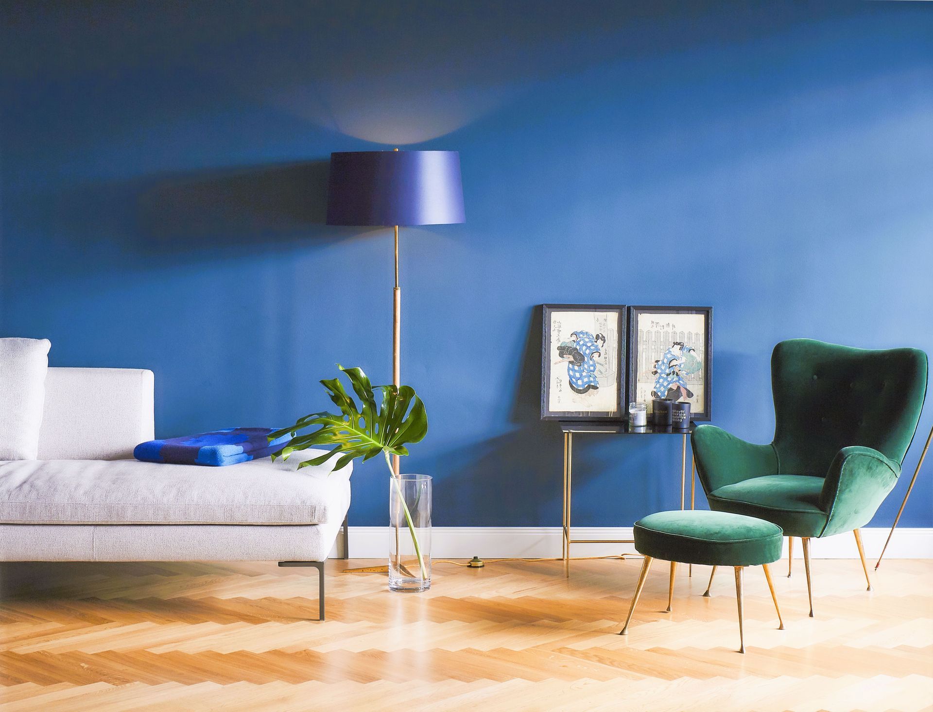Ein Wohnzimmer mit blauen Wänden, einer Couch, einem Sessel und einer Lampe.
