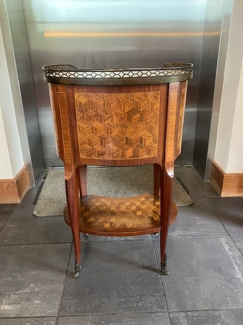 Small wooden upholstered chair with a rounded back, centered on a tiled floor against a metallic wall.