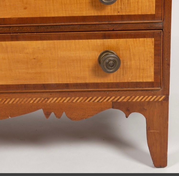 Close-up of a wooden dresser drawer with brass knob and carved foot detail