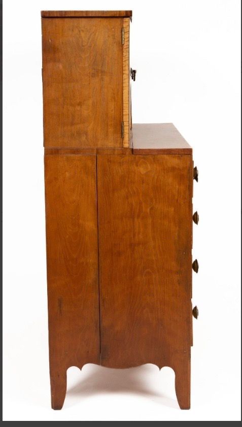 Side view of a tall wooden cabinet with a stepped top and small drawers, on a white background
