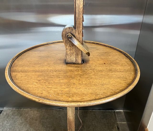 Round wooden table with a central vertical post and a curved support bracket, viewed from above.