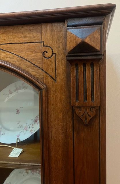 Close-up of carved wooden cabinet corner with a mirrored door and decorative trim