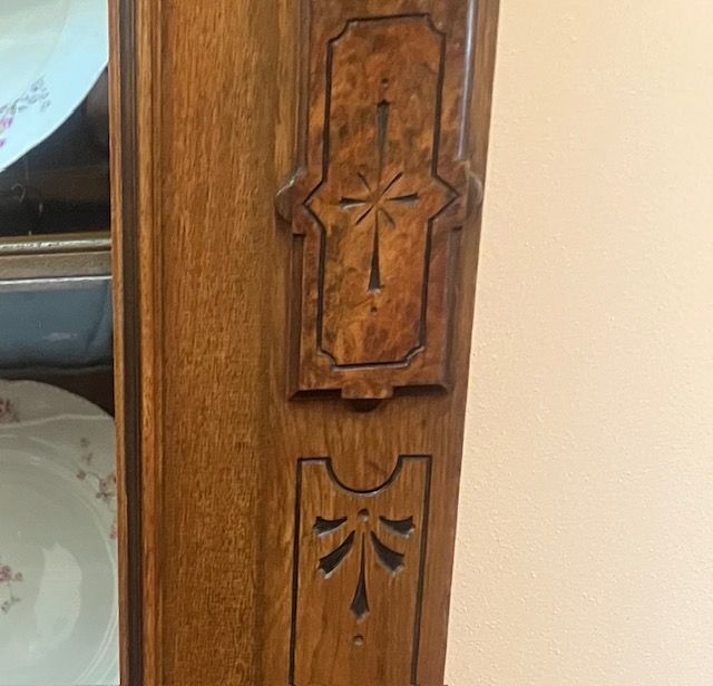 Close-up of carved wooden cabinet trim with decorative geometric inlay.