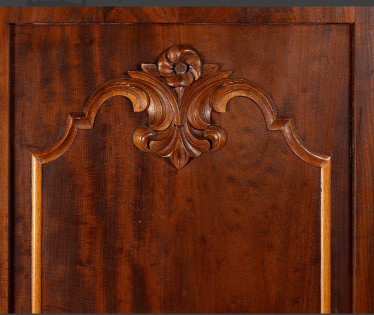Close-up of a carved wooden cabinet door with ornate floral detail and dark brown finish