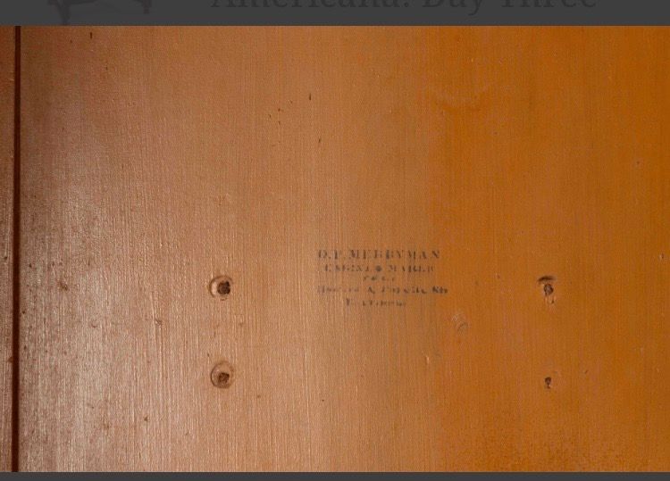 Wooden panel with small holes and a faint centered label or stamp.