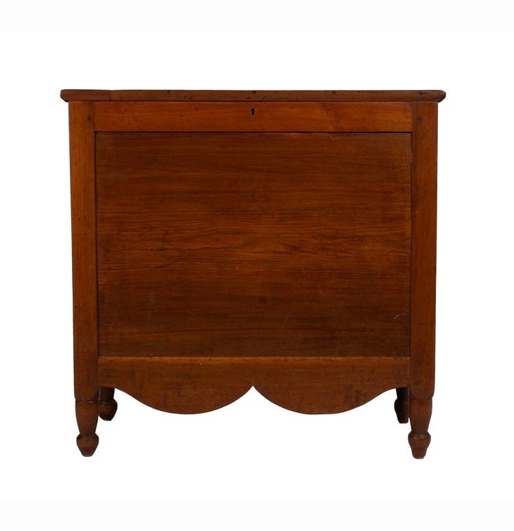 Brown wooden cabinet with scalloped lower edge and short turned legs on a white background