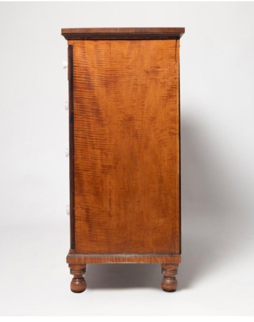 Tall wooden cabinet with a polished orange-brown finish and small turned legs against a white background