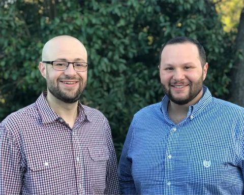 Two men are standing next to each other and smiling for the camera.