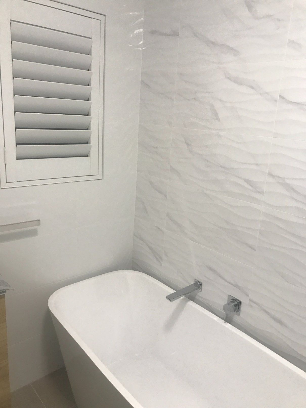 White Bathtub Against Textured White Tile Wall, With Window and Towel Rack — Worrall Tiling in South West Rocks, NSW