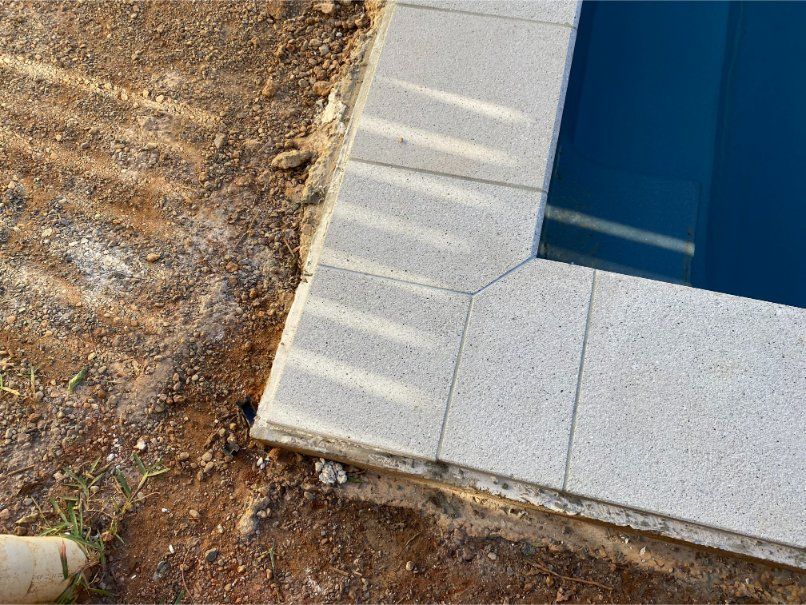 Pool Edge With Light Gray Tiles and Water, Next to Dirt and Grass — Worrall Tiling in Port Macquarie, NSW