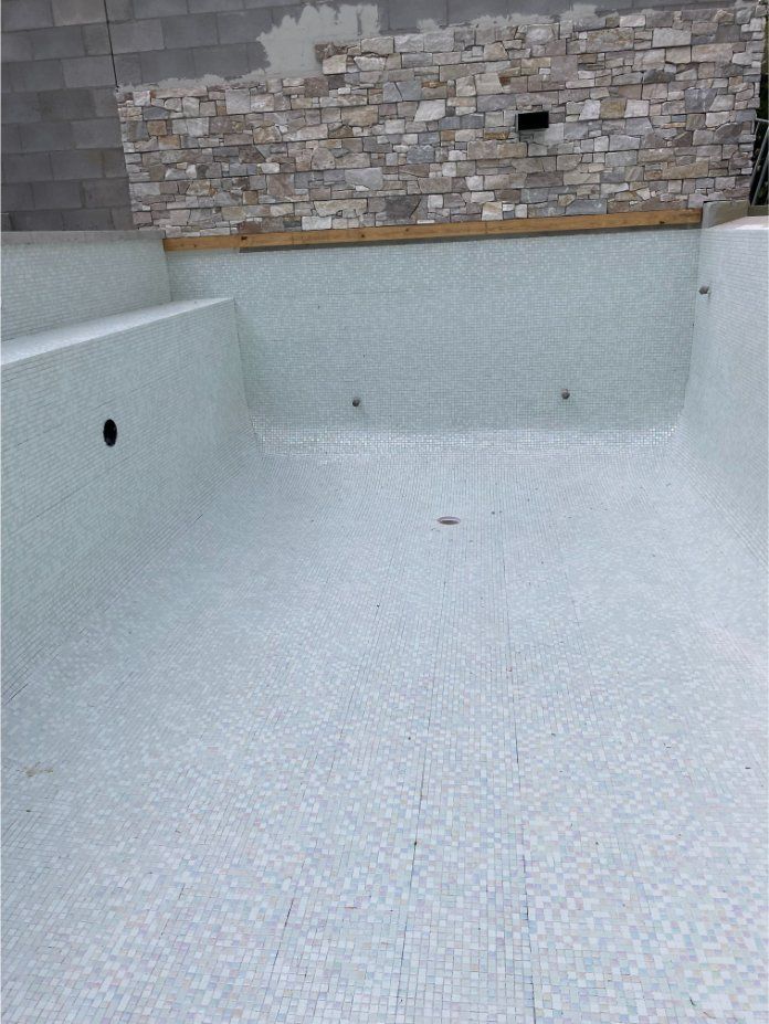 Empty Swimming Pool Tiled With Light Blue Mosaics, Under Construction — Worrall Tiling in Crescent Head, NSW