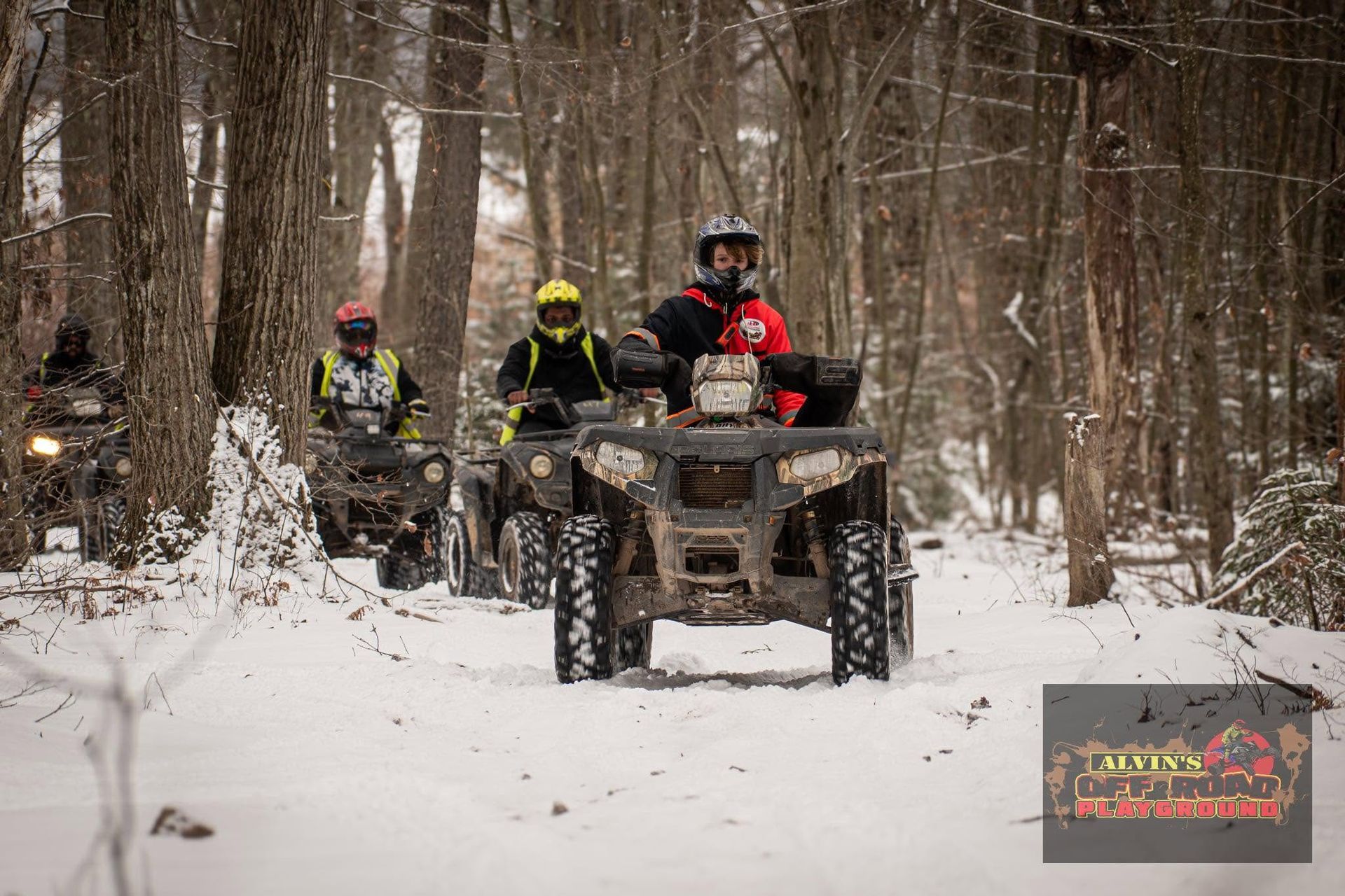 Group ATV riders exploring a snow-covered forest trail