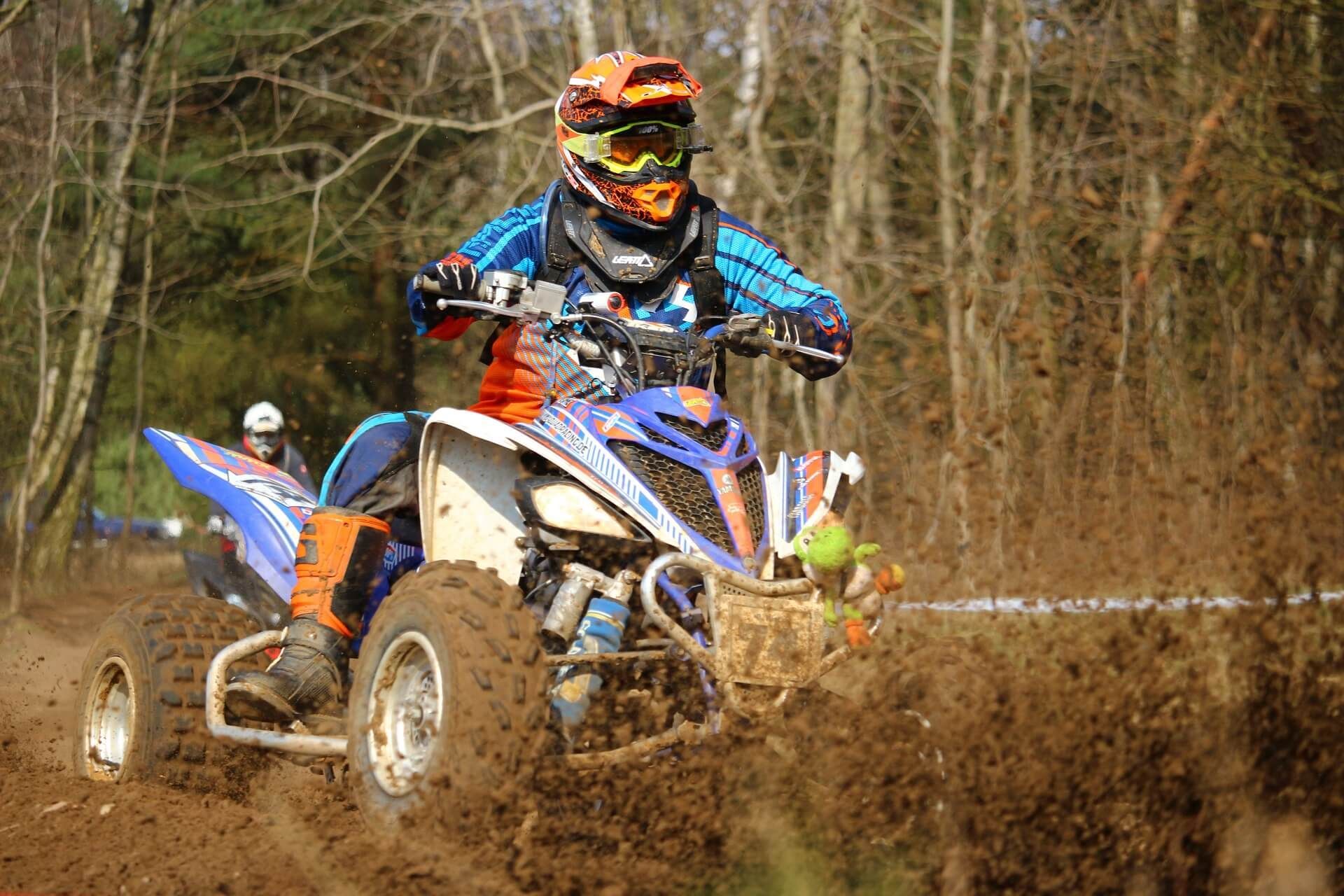 A man is riding a dirt bike through the mud.