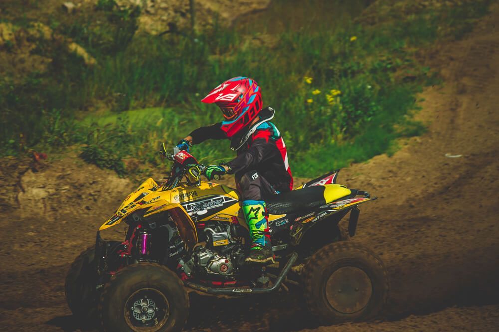 A person is riding a four wheeler on a dirt road.
