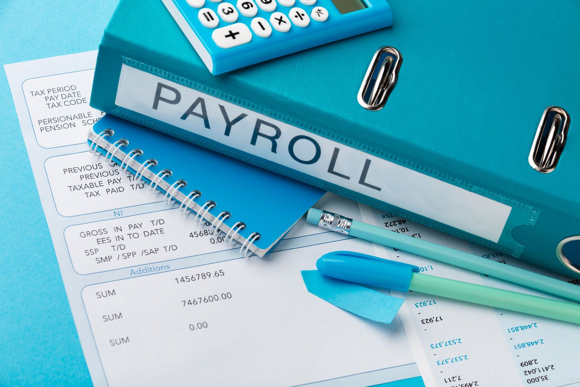 Blue payroll folder, calculator, notepad, pen, and document on a blue surface.