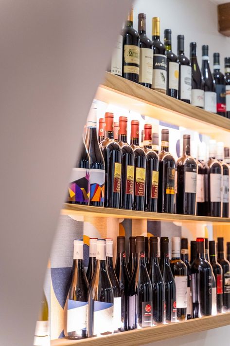 Scaffali pieni di bottiglie di vino assortite in una vetrina ben illuminata.