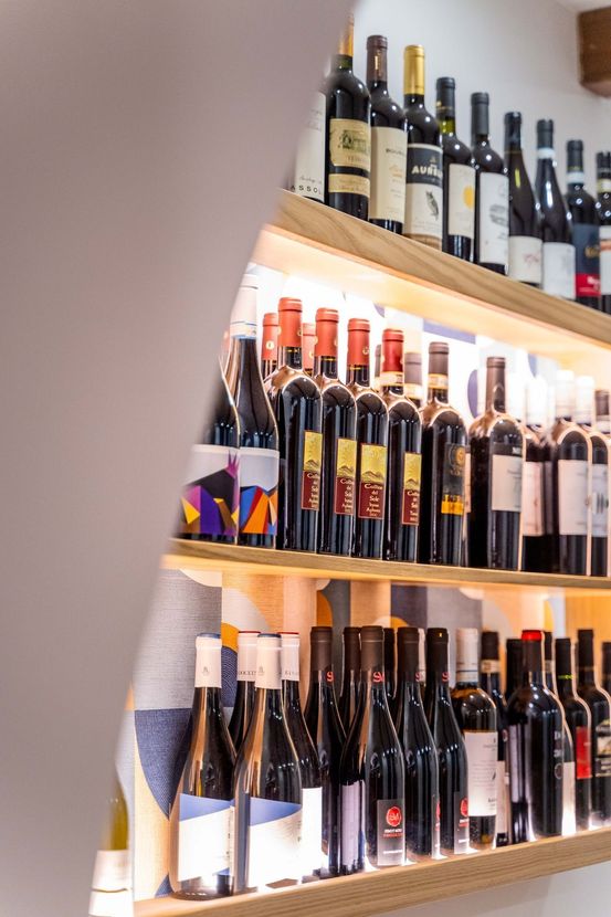 Scaffali pieni di bottiglie di vino assortite in una vetrina di un negozio.