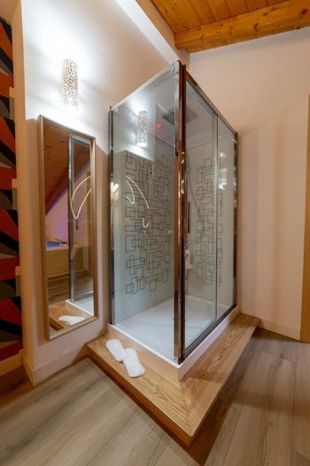 Box doccia moderno con vetro satinato in un bagno con finiture in legno.