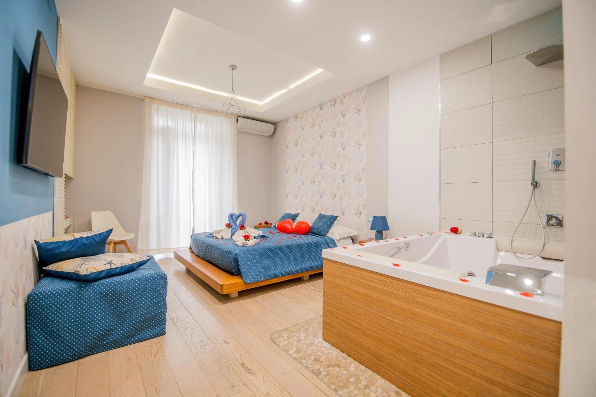 Camera da letto moderna con due letti singoli blu, vasca idromassaggio e luce bianca soffusa.