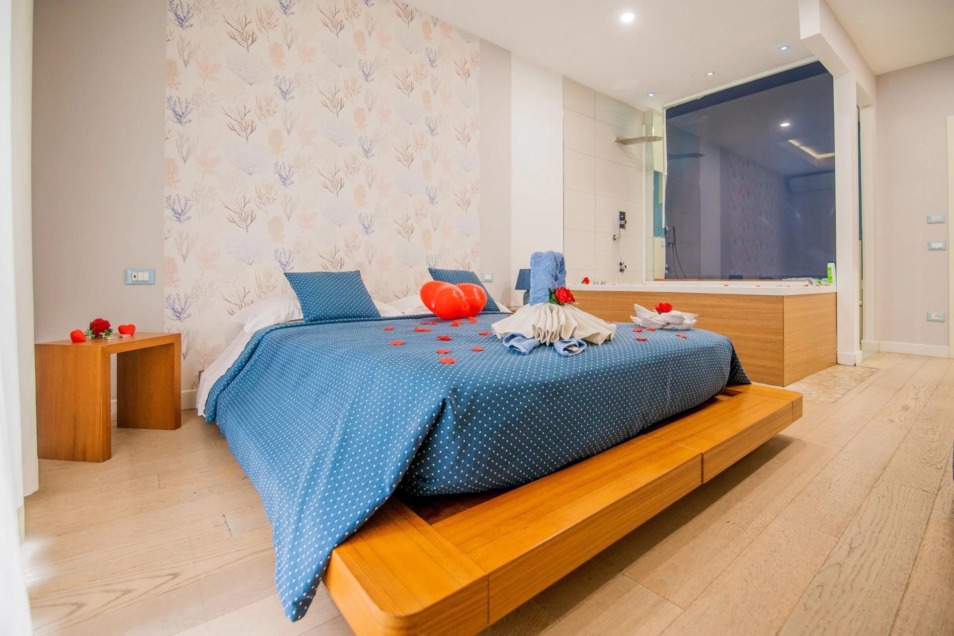 Camera da letto moderna con copriletto blu, letto a piattaforma in legno e pavimento in legno chiaro.