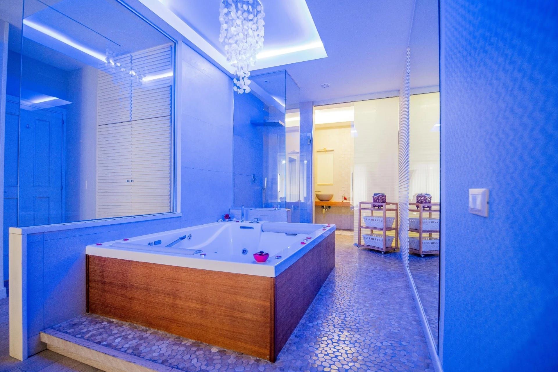 Bagno spa illuminato di blu con vasca idromassaggio angolare e pavimento piastrellato.