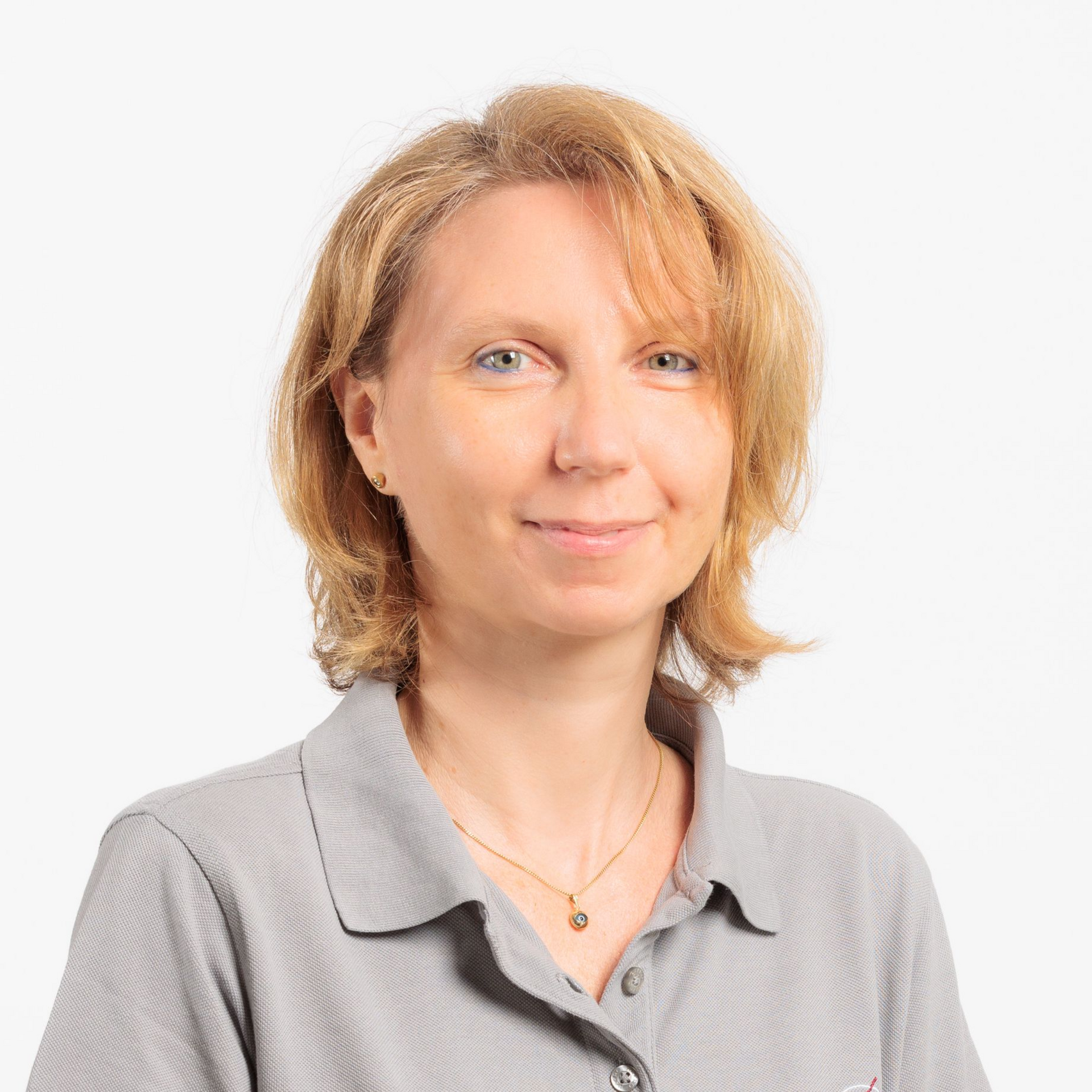 Frau mit blonden Haaren und grauem Hemdkragen, lächelnd vor weißem Hintergrund.