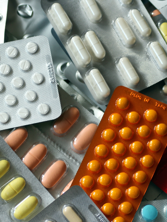 Tabletten in verschiedenen Blisterpackungen, in unterschiedlichen Farben und Formen, verstreut auf einer Oberfläche.