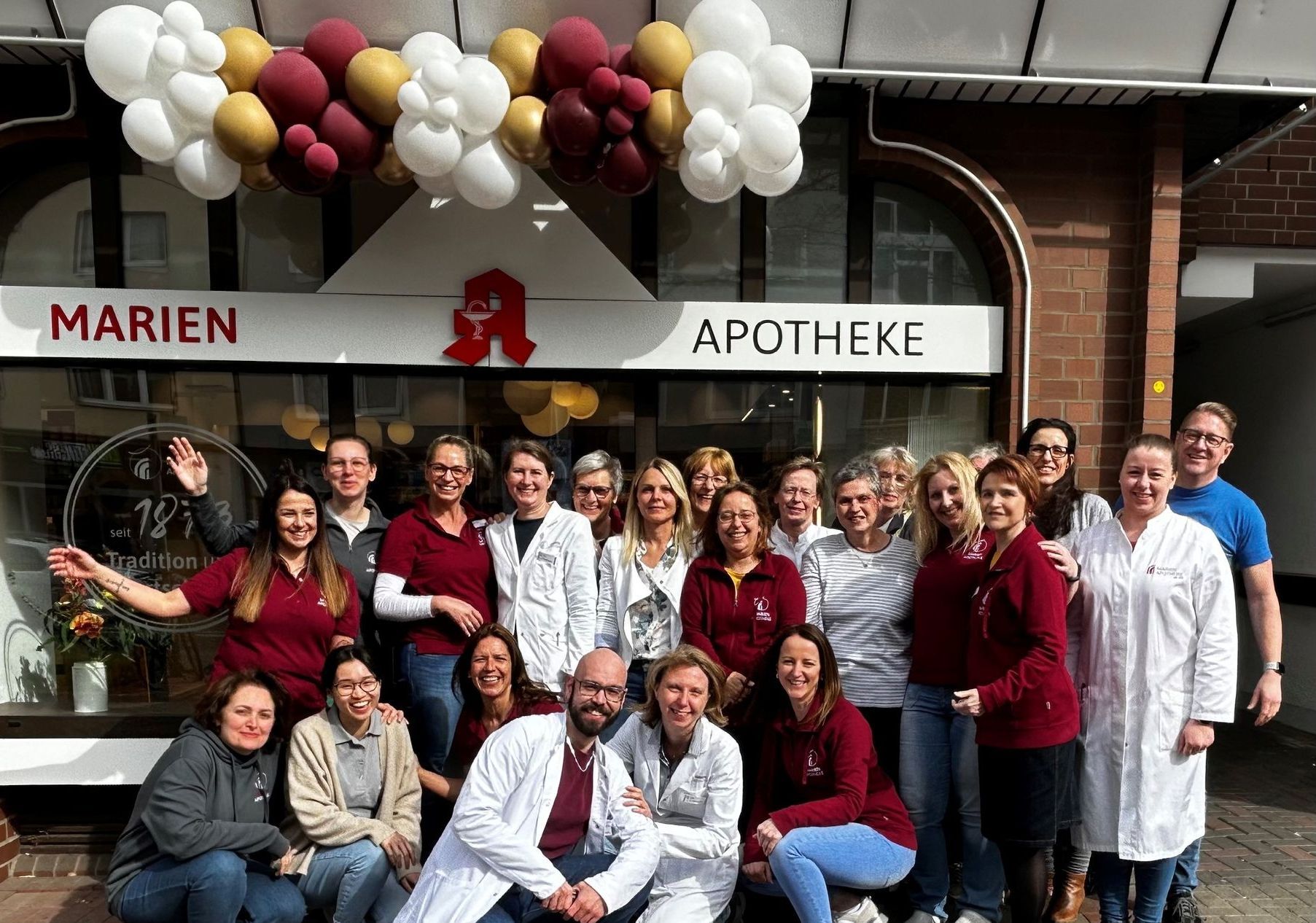 Eine Gruppe von Menschen posiert vor einer Apotheke für ein Foto.