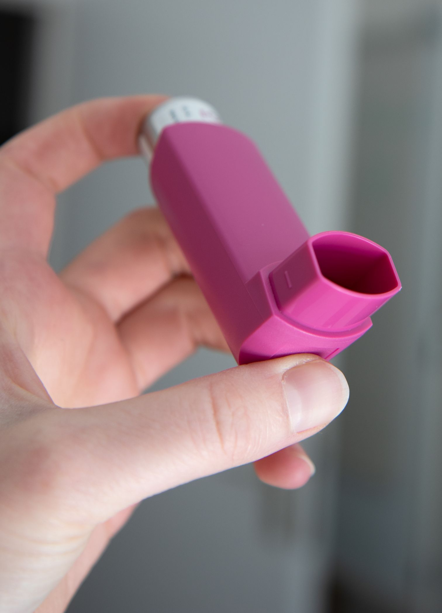 Eine Hand hält einen rosa Inhalator.