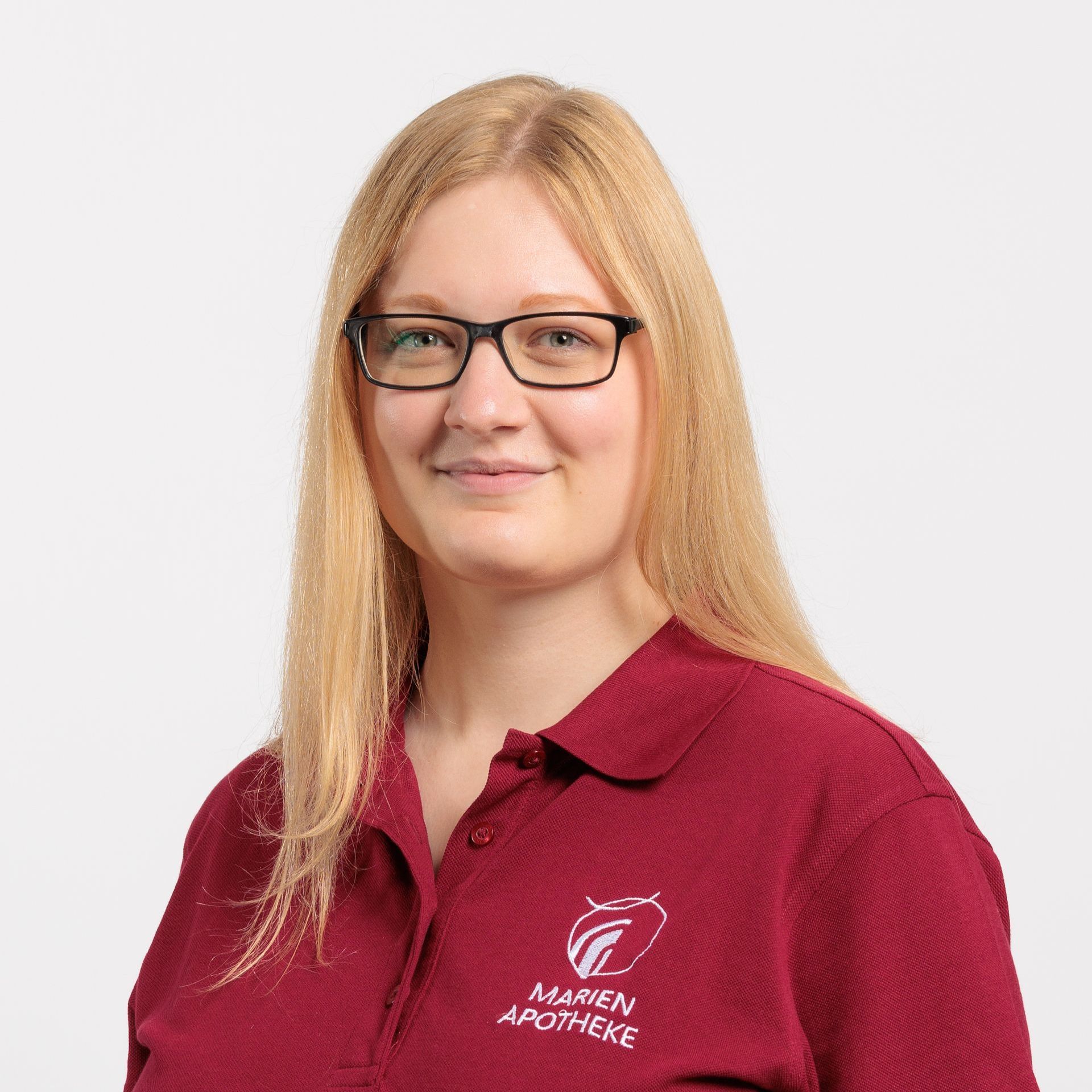 Eine Frau mit Brille und rotem Hemd lächelt in die Kamera.