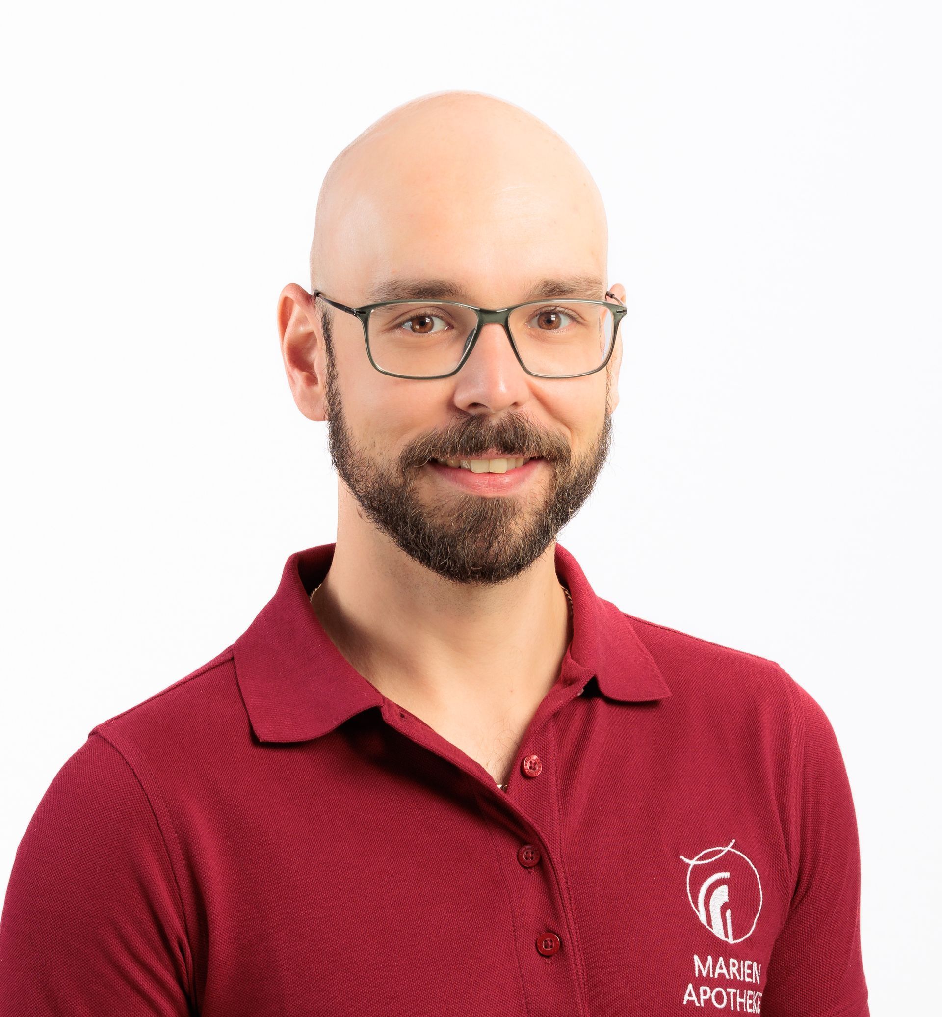 Ein kahlköpfiger Mann mit Bart, Brille und kastanienbraunem Poloshirt