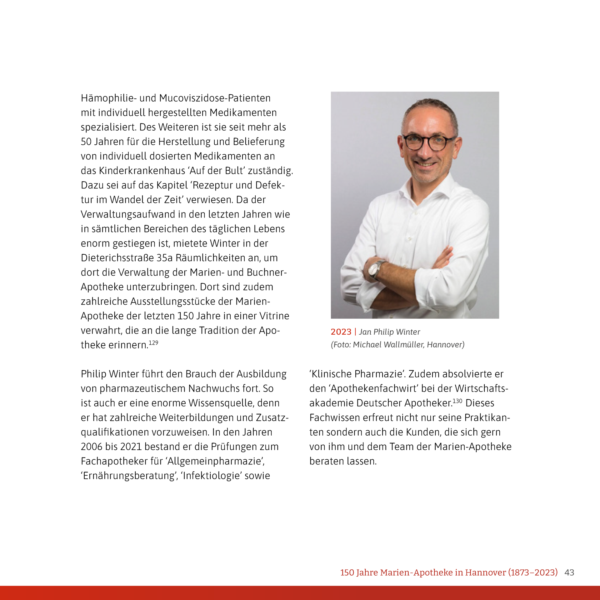 Ein Mann in einem weißen Hemd und einer Brille steht mit verschränkten Armen da.