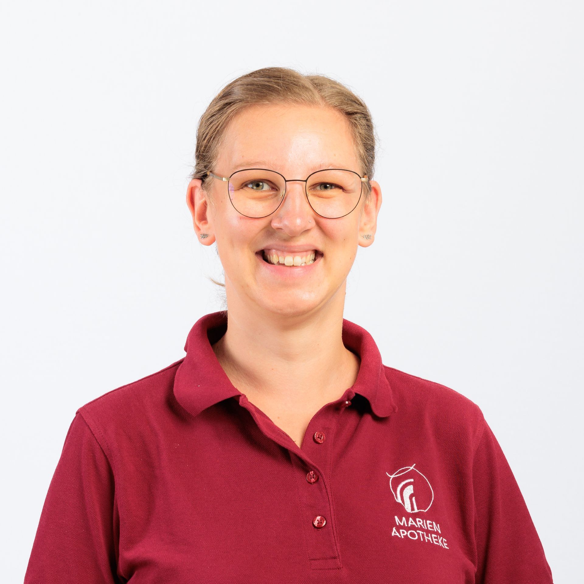 Eine Frau mit Brille und kastanienbraunem Hemd lächelt in die Kamera.