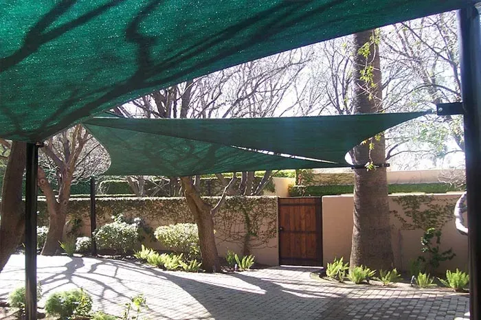 A green shade covering a parking lot with trees in the background