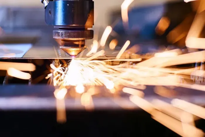 A machine is cutting a piece of metal with sparks coming out of it.
