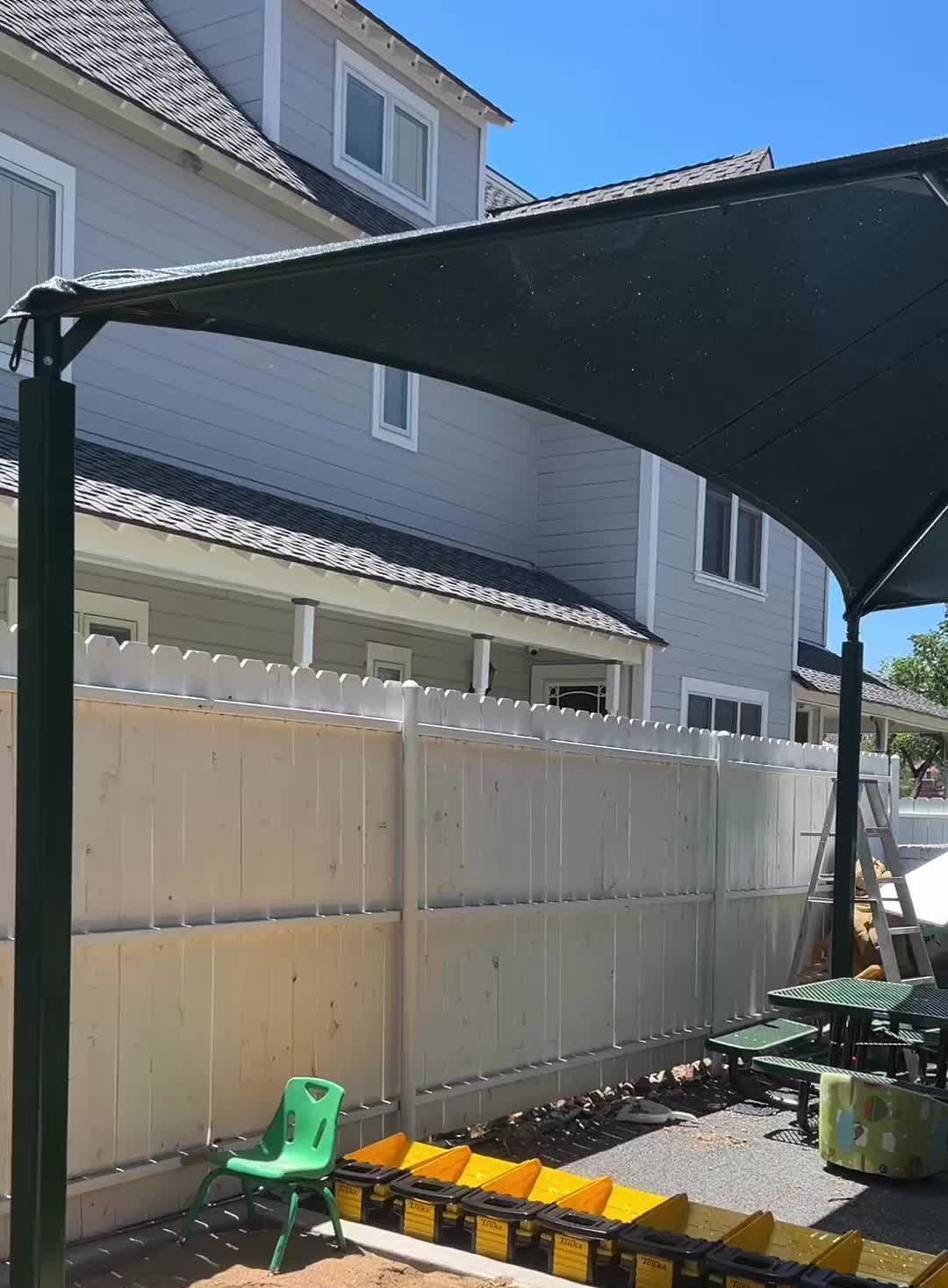 A green chair sits under a shaded area in front of a house