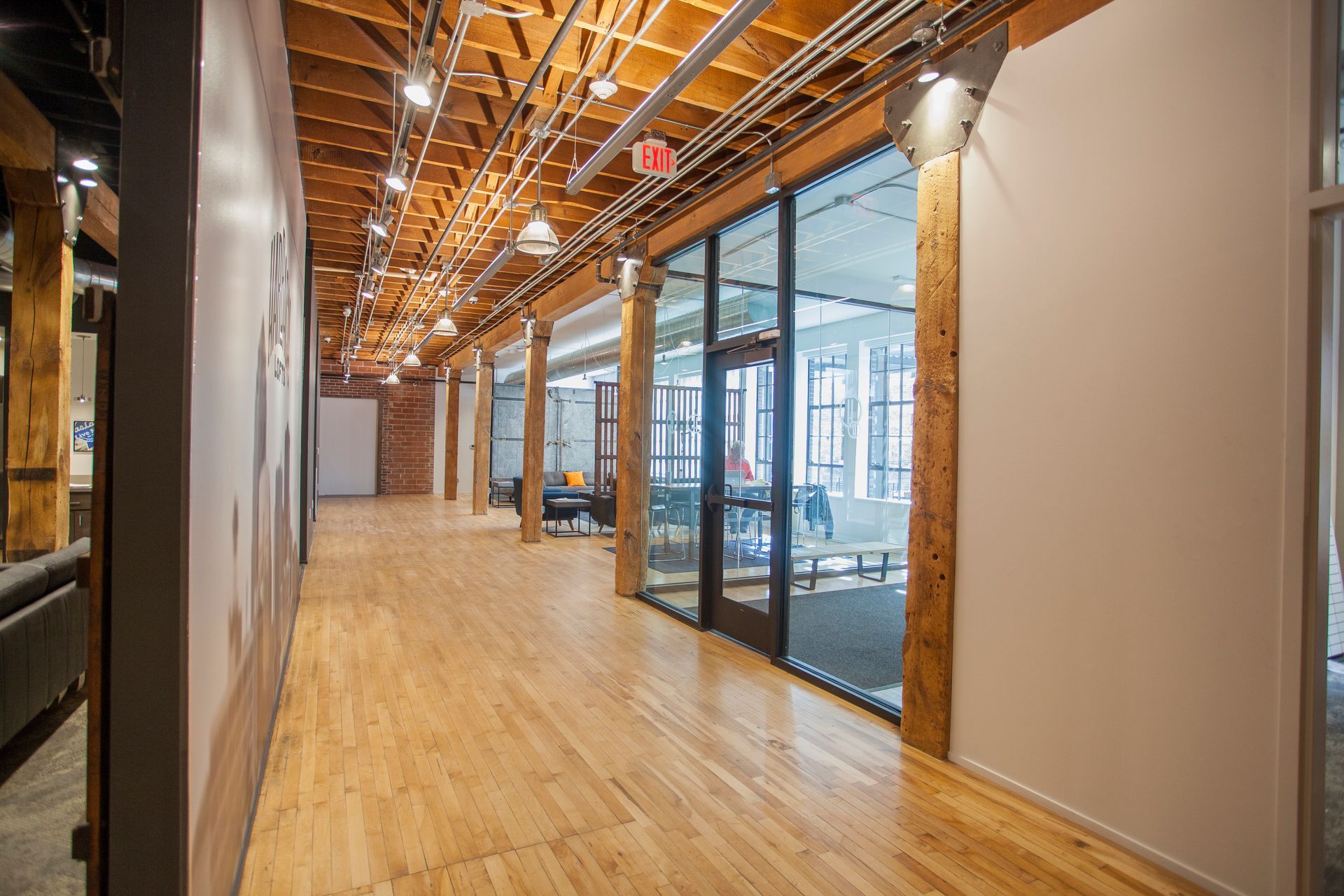 a long hallway in a building with wooden floors and glass doors .