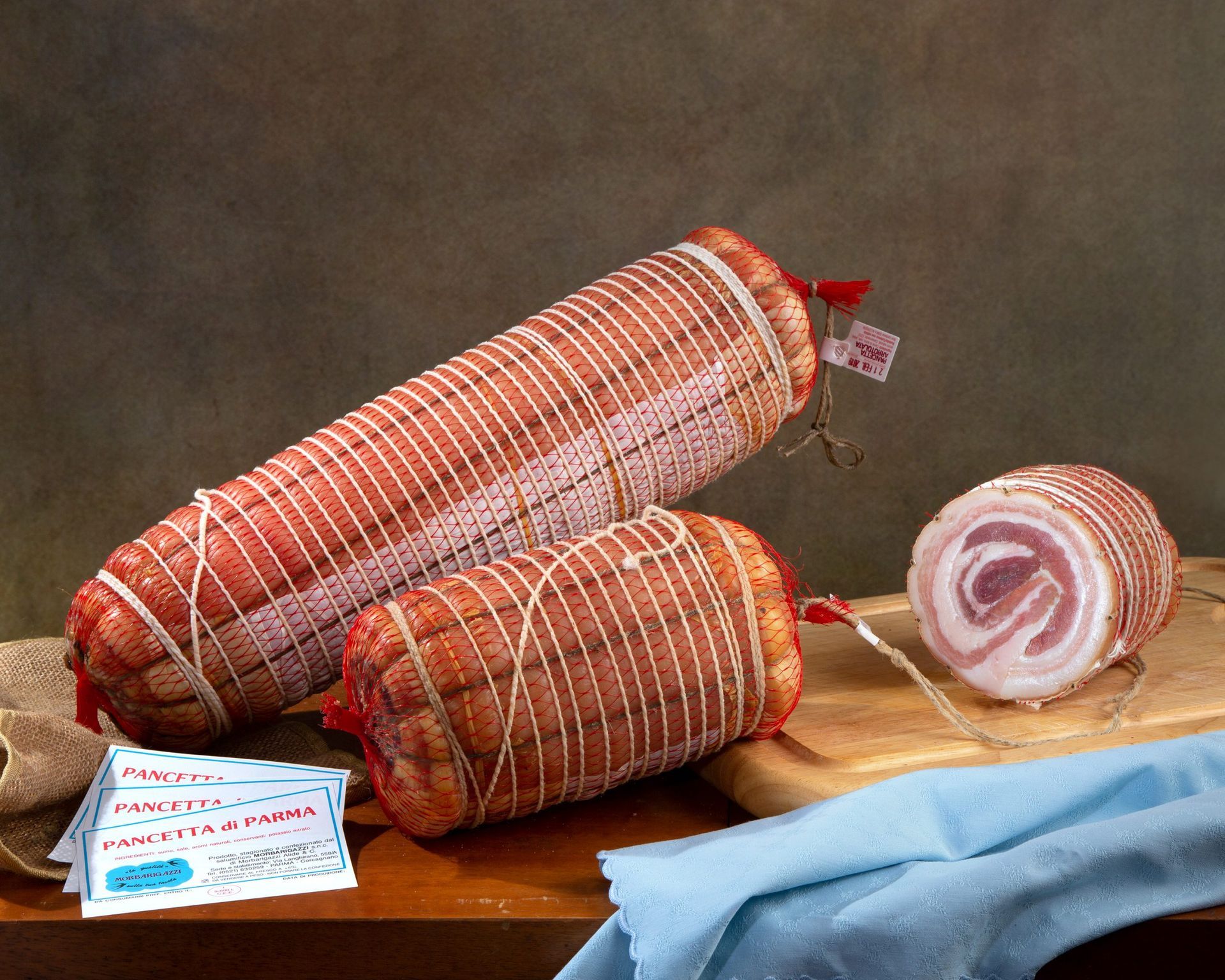 Due rotoli di pancetta sono appoggiati su un tavolo di legno