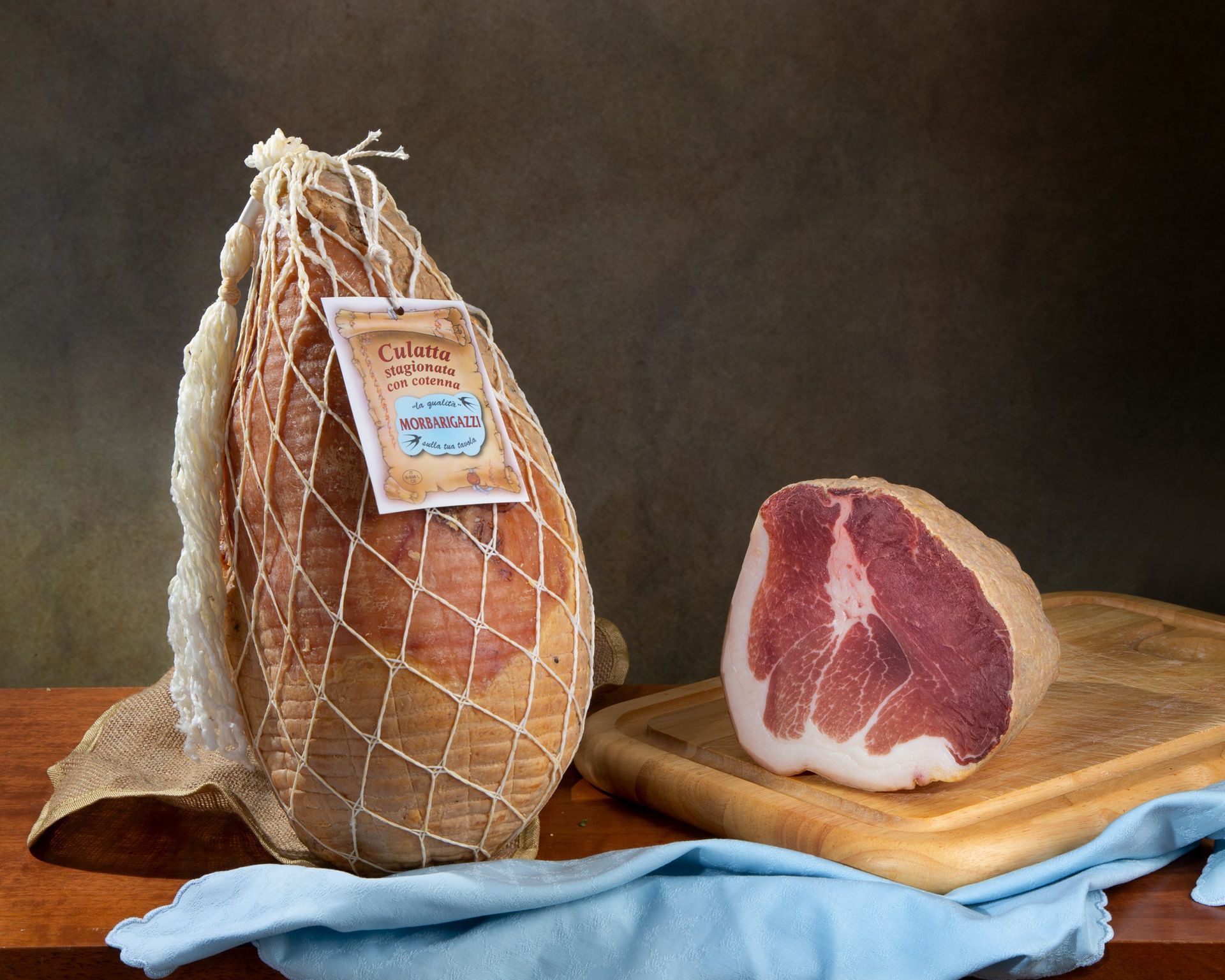 Un pezzo di prosciutto è su un tagliere accanto a un pezzo di pane