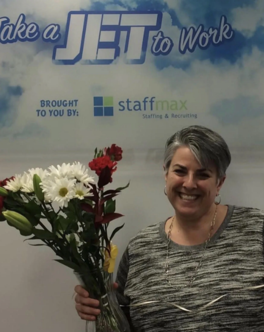 Woman smiling, holding flowers, in front of