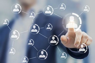 Man in a suit touching a digital network of connected user icons.