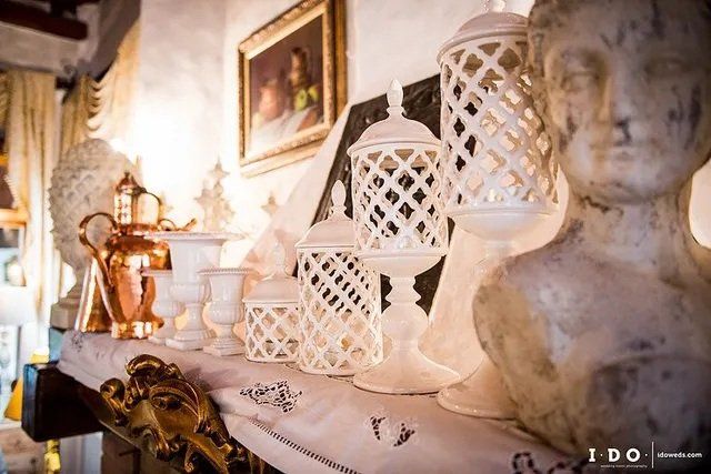 Oggetti decorativi bianchi disposti su uno scaffale, tra cui lanterne e un busto.