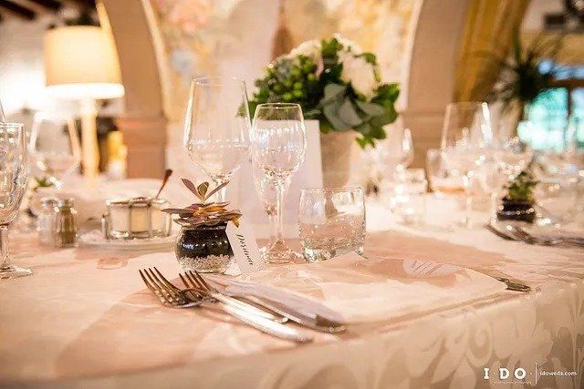 Elegante apparecchiatura della tavola con posate, bicchieri e composizioni floreali.