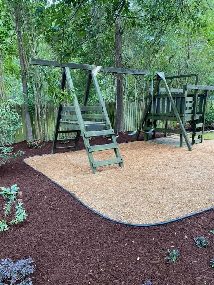 A wooden swing set is sitting on top of a pile of mulch in a backyard.
