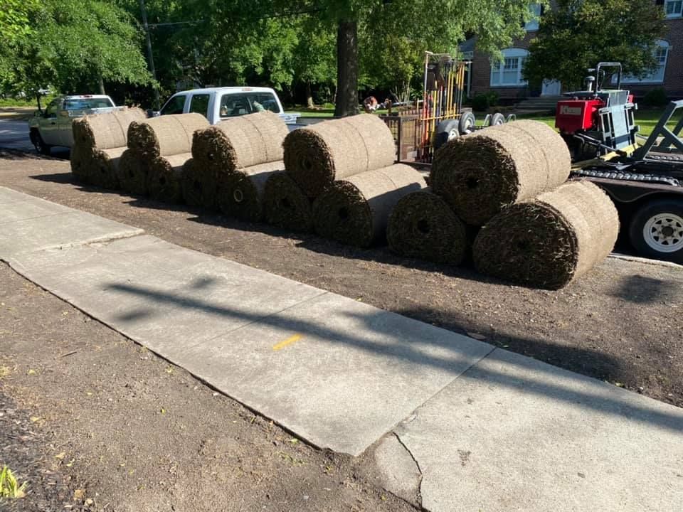 A row of hay bales are stacked on top of each other on a sidewalk.