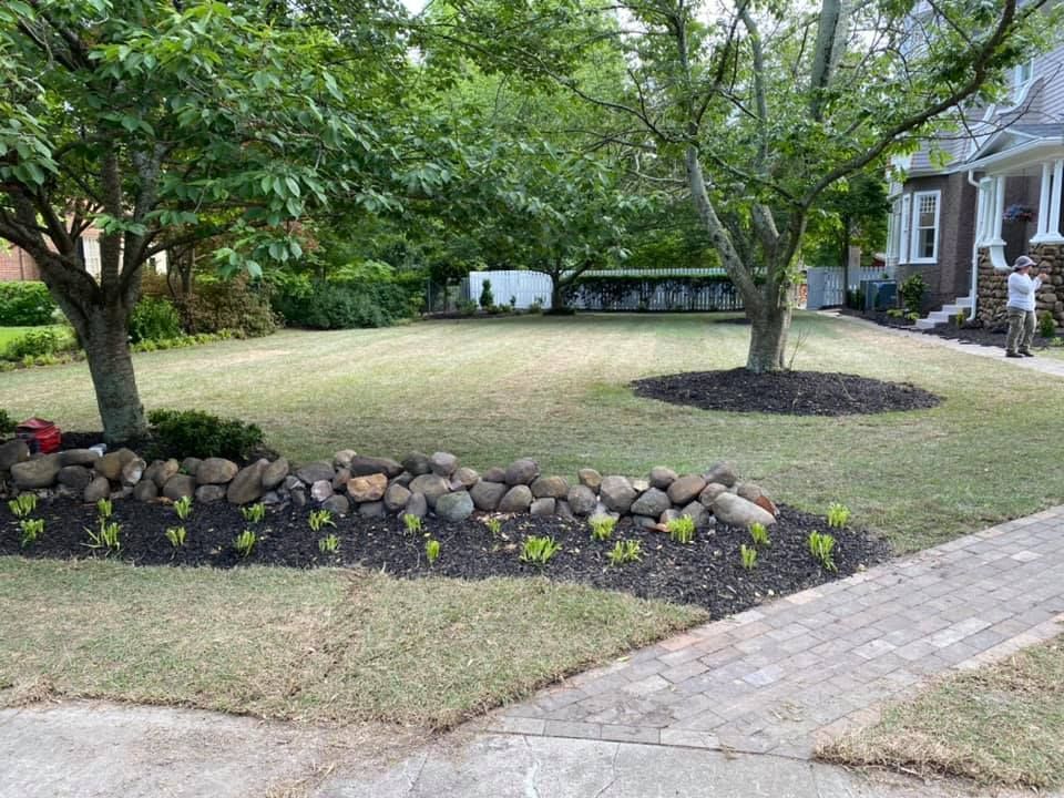 A man is standing in front of a house with a lush green lawn.
