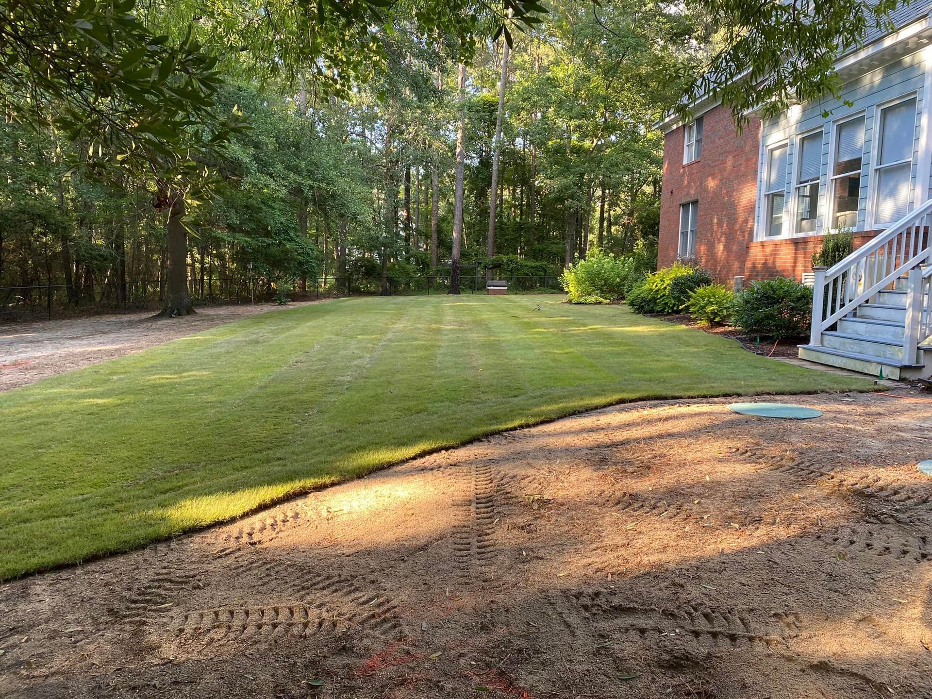 A large lush green lawn in front of a brick house.