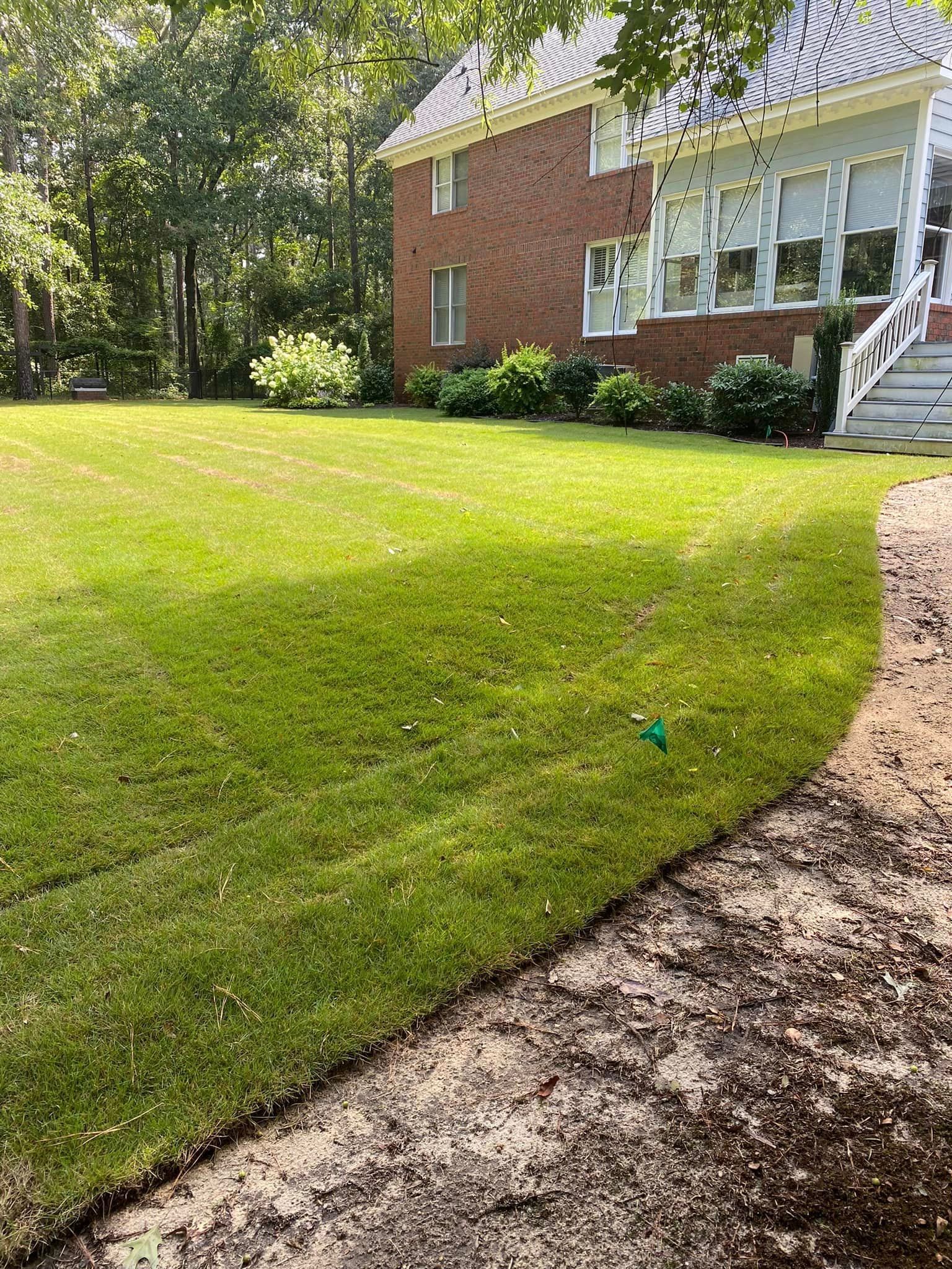 A large brick house with a lush green lawn in front of it.