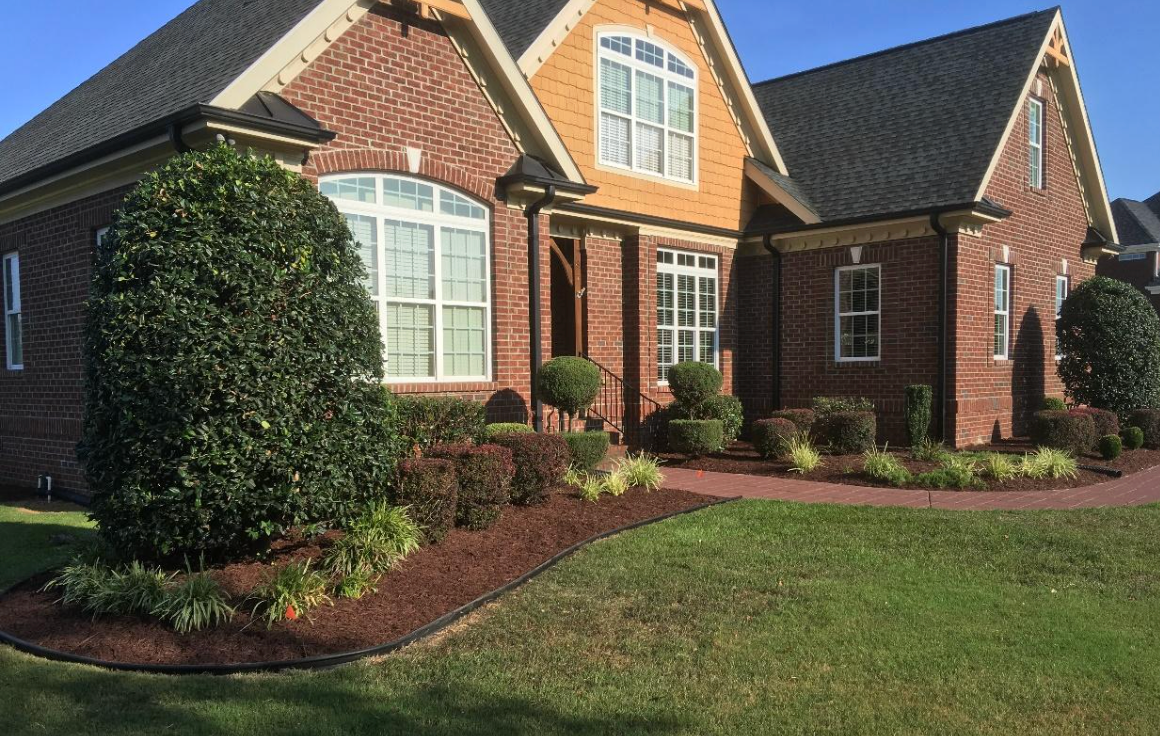 A large brick house with a lush green lawn in front of it.