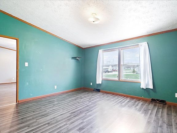 An empty room with green walls and wooden floors.